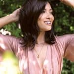 Woman with dark brown layered wig outdoors, smiling and enjoying nature.